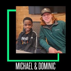 Michael and Dominic sit next to each other, smiling at the camera. There is a decorative green square in the background, and the names 