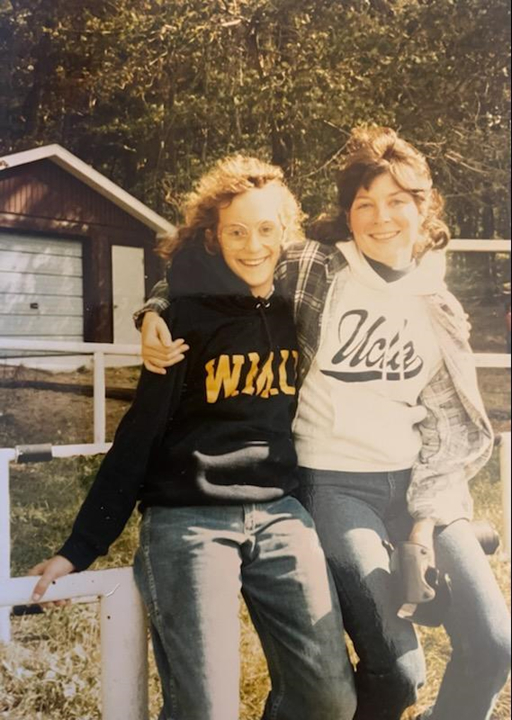 Melissa and Maureen outside wearing hoodies, smiling at the camera with their arms around one another's shoulders.