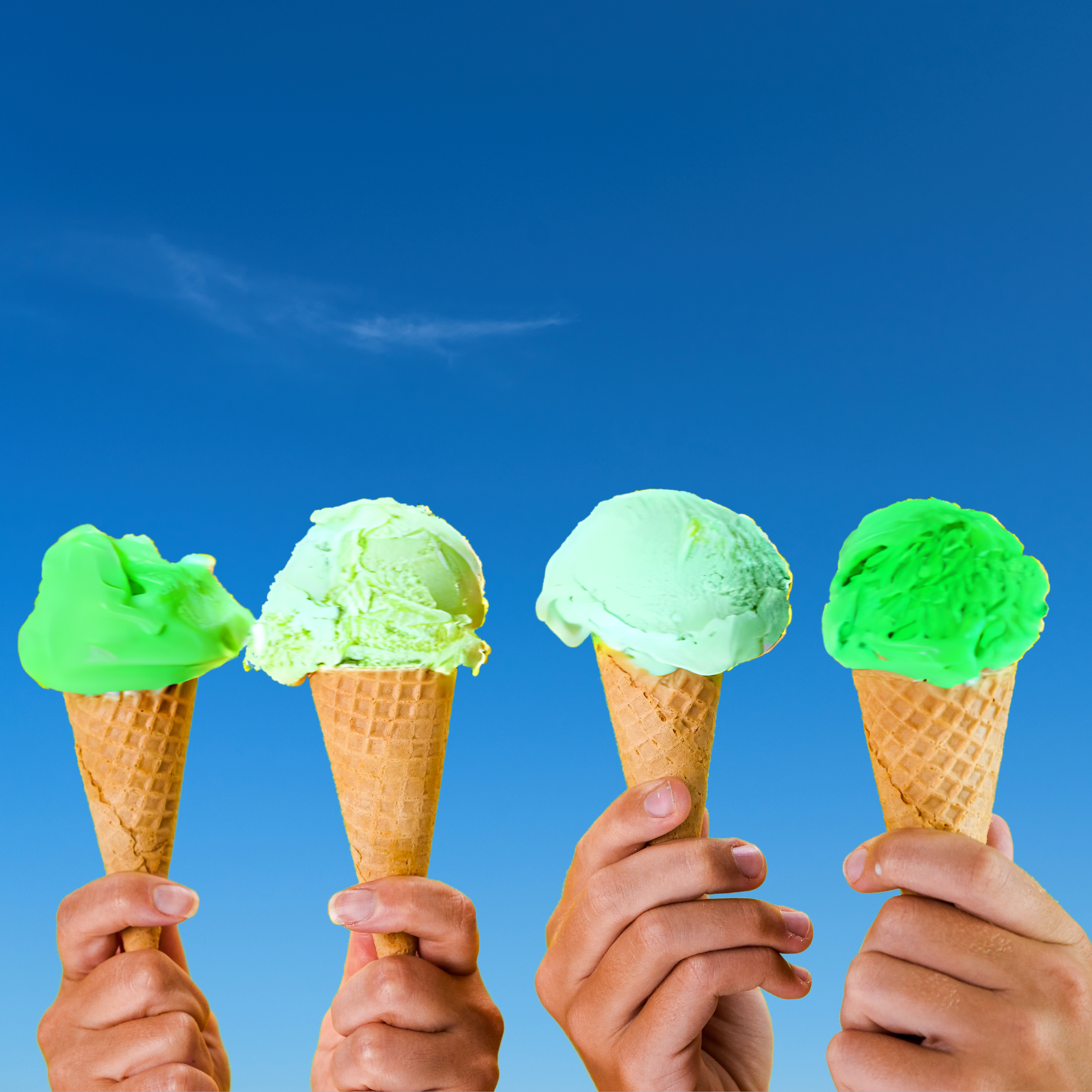 Different hands holding up different shades of green ice cream cones