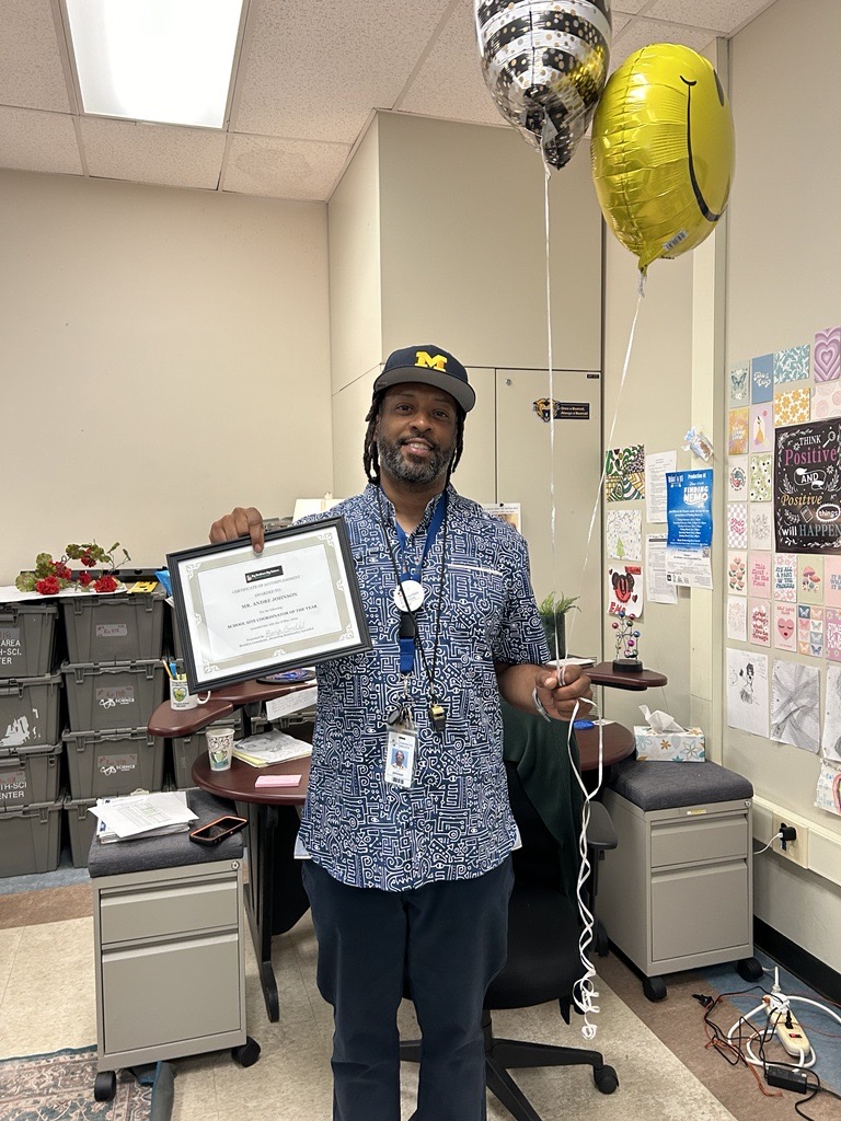 Andre, holding balloons and a certificate.