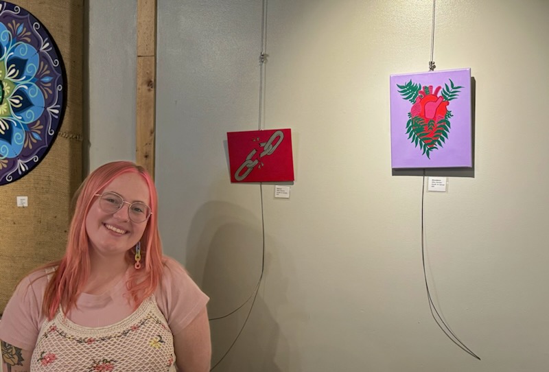Afton stands next to some art, smiling.