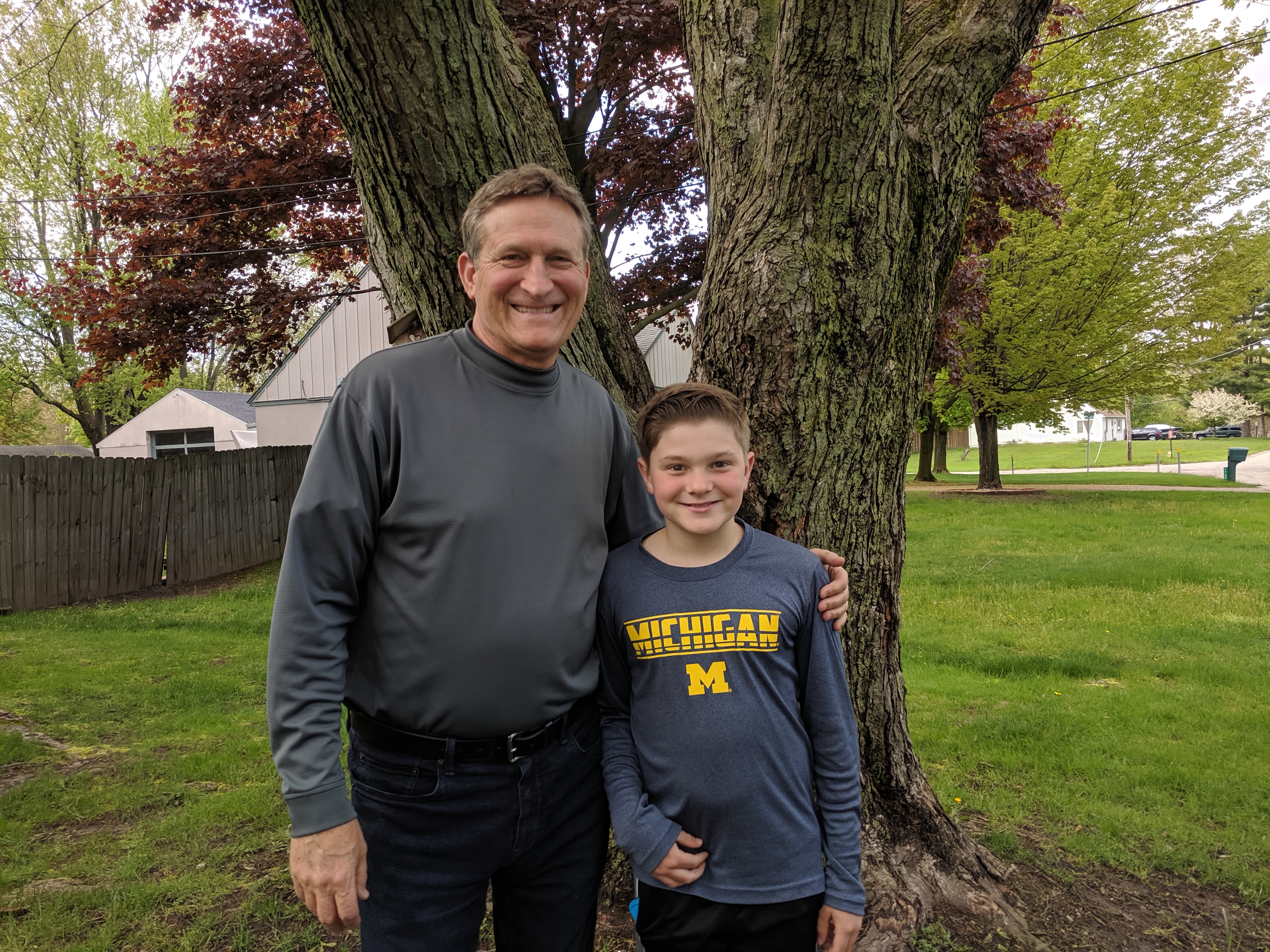 Scott and Colin standing in front of a tree outside, smiling at the camera.